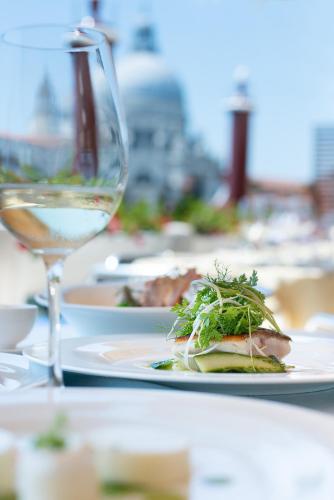 a table with plates of food and a glass of wine at Monaco & Grand Canal in Venice