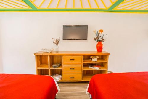 a room with a television on a table with two beds at Hotel Mirador de Boquia Salento in Salento