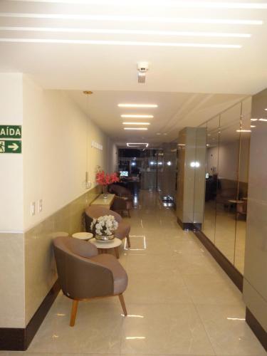 a hallway with chairs and a table in a building at Magnífico APARTAMENTO de Charme - 3 quartos AR CONDICIONADOS SPLIT - Beira Mar, 2 banheiros, 2 Vagas Garagem, 4 Varandas, 2 Elevadores, Redes para Descanso, Wi-Fi, Air Fryer, Disney Plus, HBO Max, Guarda Sol, Cadeiras de Praia e Caixa Térmica in Guarapari