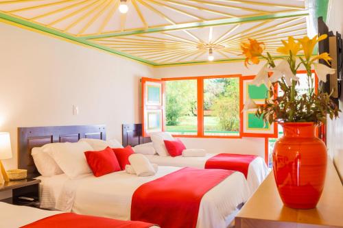 1 dormitorio con 2 camas y un jarrón con flores en Hotel Mirador de Boquia Salento, en Salento