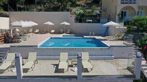a swimming pool with chairs and umbrellas next to it at Mazis Apartments in Agios Gordios