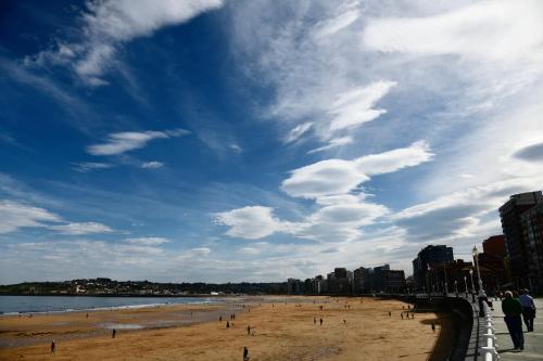 a beach with people on the sand and a cloudy sky at Hotel Zentral Gijón Rey Pelayo in Gijón
