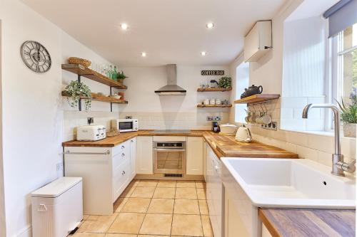 a kitchen with white cabinets and a sink at Host & Stay - Waterleap Cottage in Ovingham