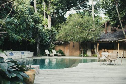 una piscina con sillas, una mesa y una casa en Pousada Capim Santo, en Trancoso