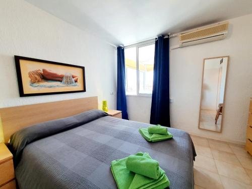 1 dormitorio con 1 cama con toallas verdes en Fuengirola Towers, en Fuengirola