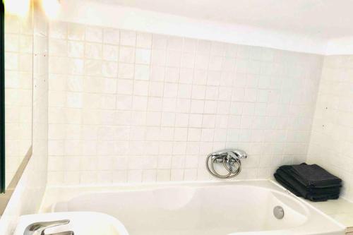 La salle de bains est pourvue de carrelage blanc et d'une baignoire avec une valise. dans l'établissement Cannes Lions Rue Montaigne, 200m Palais des festivals, à Cannes