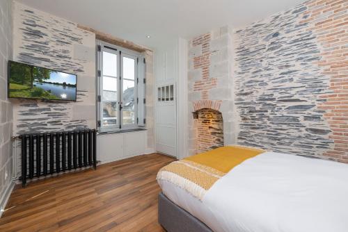 una camera da letto con un muro di mattoni, un letto e una TV di Hyper Centre 16 rue Valdemaine ad Angers