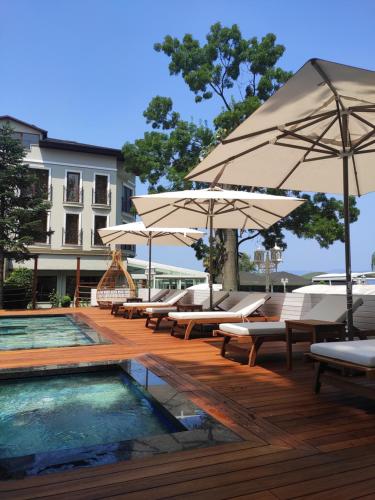 a pool with lounge chairs and umbrellas next to a building at Lale Hotel in Sapanca