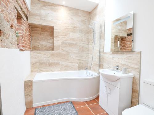 a bathroom with a white tub and a sink at Little Barn in Whissonsett