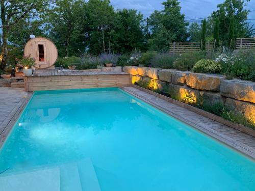 a swimming pool in a backyard with a retaining wall at Maison d'Hôtes de Charme Le Clos de la Fontaine Piscine & SPA in Labastide-Marnhac