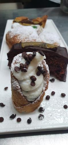 a plate with three donuts and a piece of cake at Ines bed and breakfast in Giardini Naxos