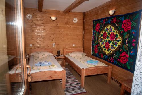 a room with two beds and a painting on the wall at Pensiunea Bontos in Budeşti