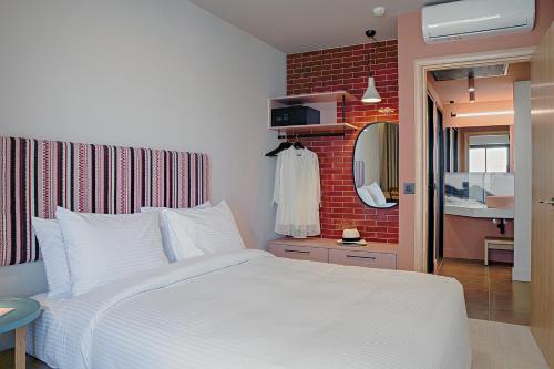 a bedroom with a white bed and a brick wall at Pavo Art Hotel in Heraklio Town