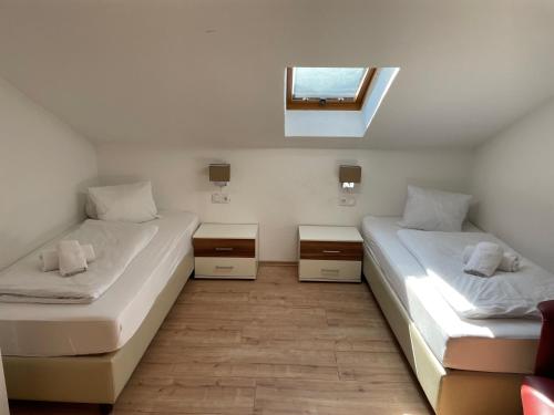 2 Betten in einem kleinen Zimmer mit Fenster in der Unterkunft Apartments Garden House in Niedernsill