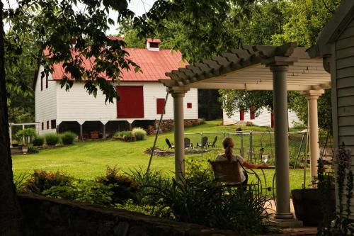 a woman standing under a pergola in a yard at South Court Inn in Luray