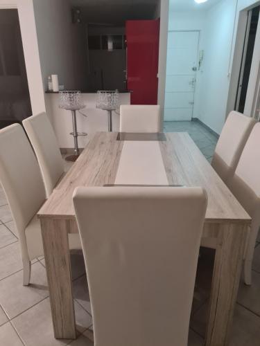 una mesa de comedor con sillas blancas alrededor en GREG HOUSE, en Pointe-à-Pitre
