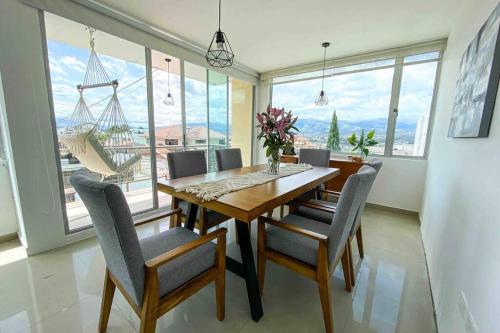 - une salle à manger avec une table, des chaises et des fenêtres dans l'établissement HERMOSO DEPARTAMENTO CON INCREIBLES VISTAS CUMBAYA, à Quito