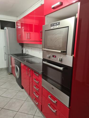 cocina roja con armarios rojos y microondas en GREG HOUSE, en Pointe-à-Pitre
