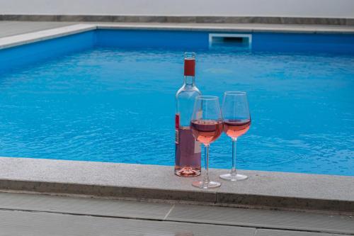 two glasses of wine sitting next to a swimming pool at Swell House in Ferrel