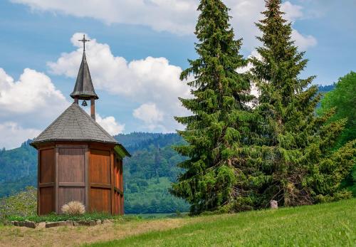 a wooden chapel and a christmas tree on a hill at Hotel-Pension Waldeck in Todtmoos