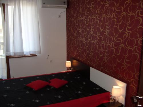 a bedroom with a black bed with red pillows at Family Hotel Malibu in Chernomorets