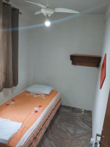 a bed in a room with a ceiling fan at Pousada Regina in Cachoeiro de Itapemirim