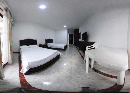a bedroom with two beds and a desk and a sink at Zahira Hotel Melgar in Melgar