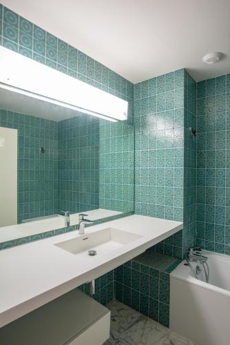 une salle de bain carrelée verte avec un lavabo et un miroir dans l'établissement 3 pièces vue mer et piscine quartier Parc Impérial, à Nice
