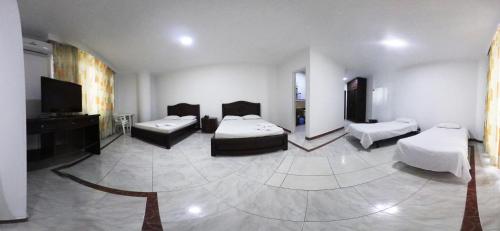 a room with three beds and a flat screen tv at Zahira Hotel Melgar in Melgar