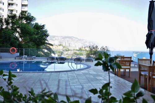 a swimming pool with tables and chairs next to a building at Madeira Regency Cliff - Adults Only in Funchal