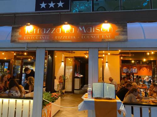 ein Restaurant mit Leuten, die davor an Tischen sitzen in der Unterkunft LA MAISON by Hotel Aldebaran in Lido di Jesolo