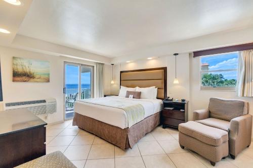 a bedroom with a bed and a chair and a window at Best Western Plus Beach Resort in Fort Myers Beach