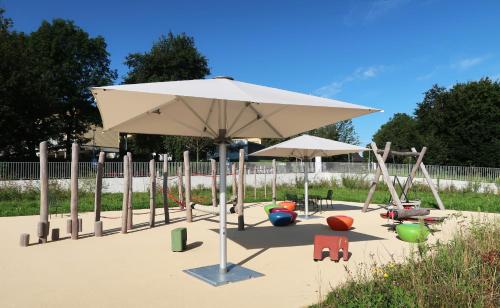 a playground with an umbrella and chairs in the sand at Hotel Sempachersee in Nottwil