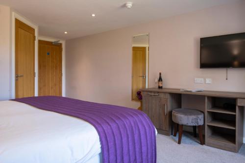a bedroom with a bed with a purple blanket at The Limes Country Lodge Hotel & Admiral Restaurant in Solihull