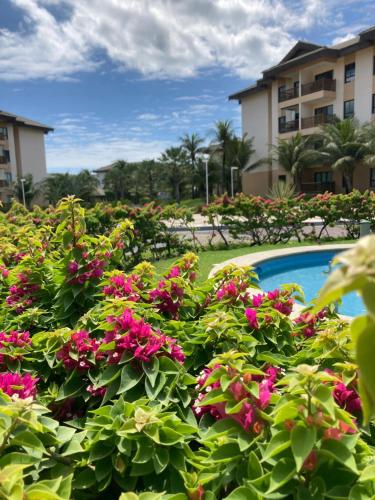 un jardín con flores rosas junto a una piscina en VG Sun Cumbuco by Bruna Mazzer en Cumbuco