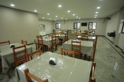 a dining room with white tables and chairs and a room with at Hotel Diamantte in Cachoeiro de Itapemirim