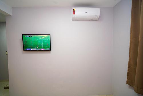 TV de pantalla plana en la pared de una habitación en Hotel Diamantte, en Cachoeiro de Itapemirim