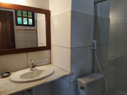 a bathroom with a sink and a mirror and a toilet at Pousada Canto De Imbassai in Imbassai