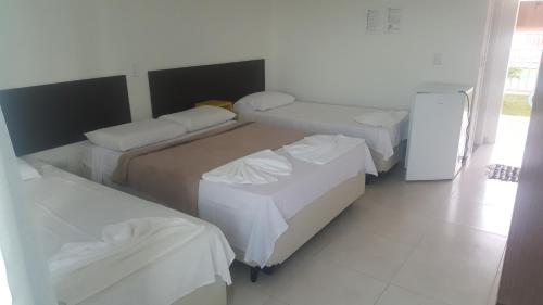 Habitación de hotel con 2 camas y nevera. en Pousada Peruíbe Ametista, en Peruíbe