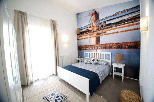 a bedroom with a bed and a painting of a ship at Dimora Mothia in Marsala