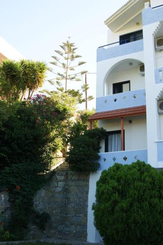 a white building with a stone walkway in front at Lofos Hotel in Plakias