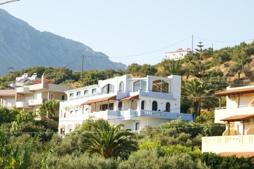 a white building on a hill with houses at Lofos Hotel in Plakias
