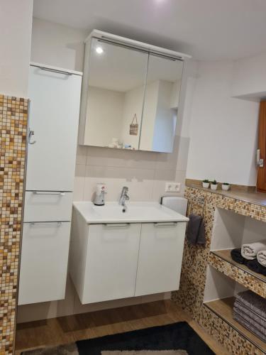 a white kitchen with a sink and a mirror at Haus Schneider in Kappel-Grafenhausen