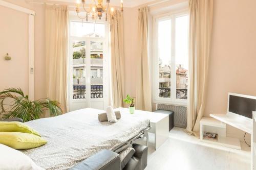 a white bedroom with a bed and a window at Cosy apartment 39M2, two steps from rue d'Antibes and Croisette in Cannes