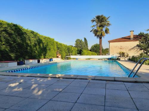 une piscine avec un palmier et un bâtiment dans l'établissement Camamelu, à Labastide-Dénat