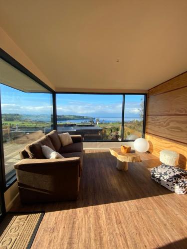 a living room with a couch and a large window at Cabañas Vista Volcanes del Sur in Llanquihue