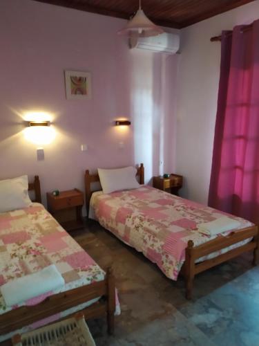 two beds in a room with pink curtains at EKTOR APARTMENTS @SWIMMING POOL in Sidari
