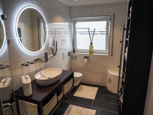 a bathroom with a sink and a toilet and a mirror at Ferienwohnung Langlitz in Rust