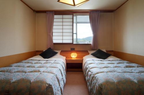 two beds in a room with a window at Kami no yama Azumaya in Kaminoyama