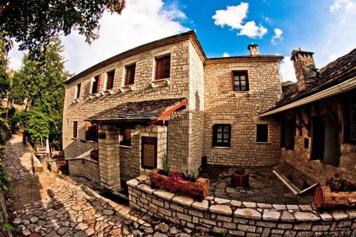 ein altes Backsteinhaus mit einer Steinterrasse davor in der Unterkunft Αρχοντικό Βογιάρου in Kalarites